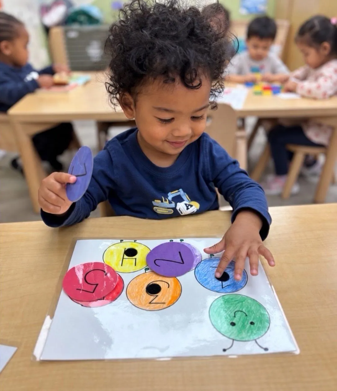 A toddler placing colored circles on a matching board